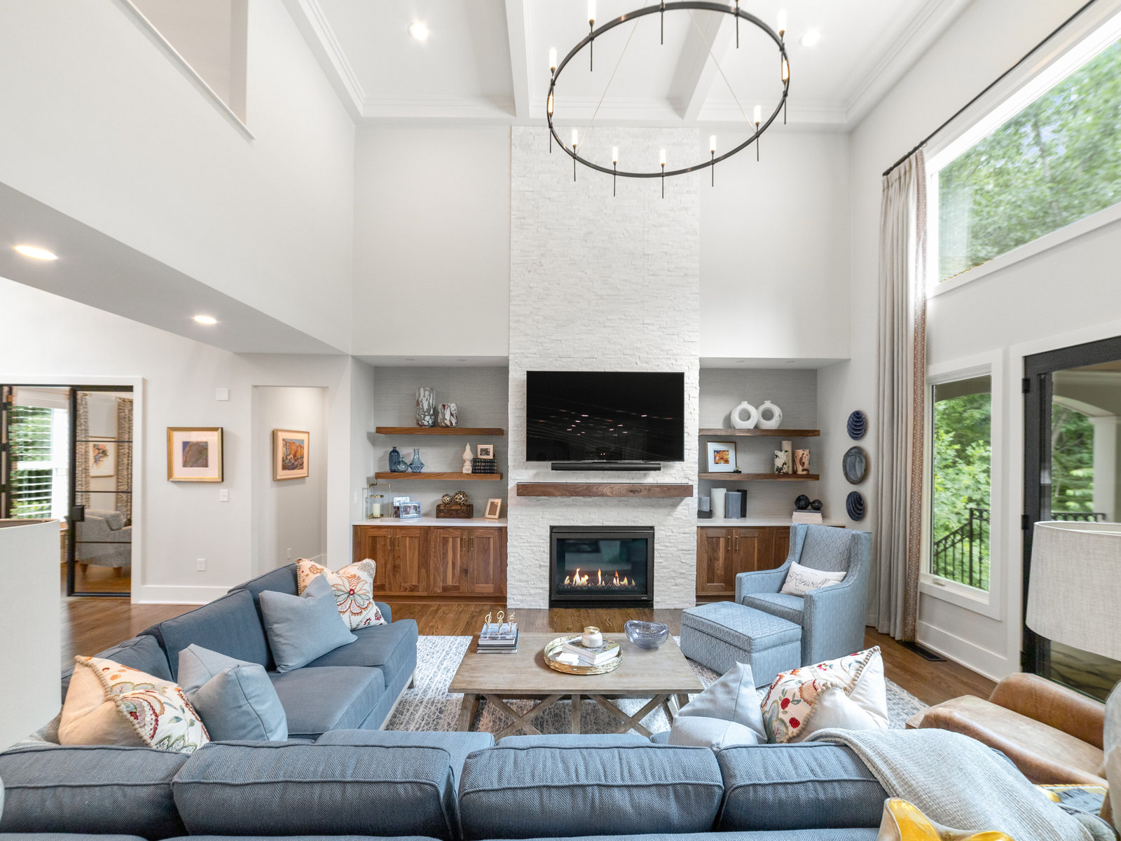 Renovated open-plan living room by All-Square Contracting with a stone fireplace, vaulted ceiling and wall of windows